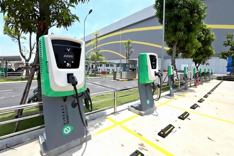 VinFast electric SUVs charging at a modern public charging station in a Vietnamese city.